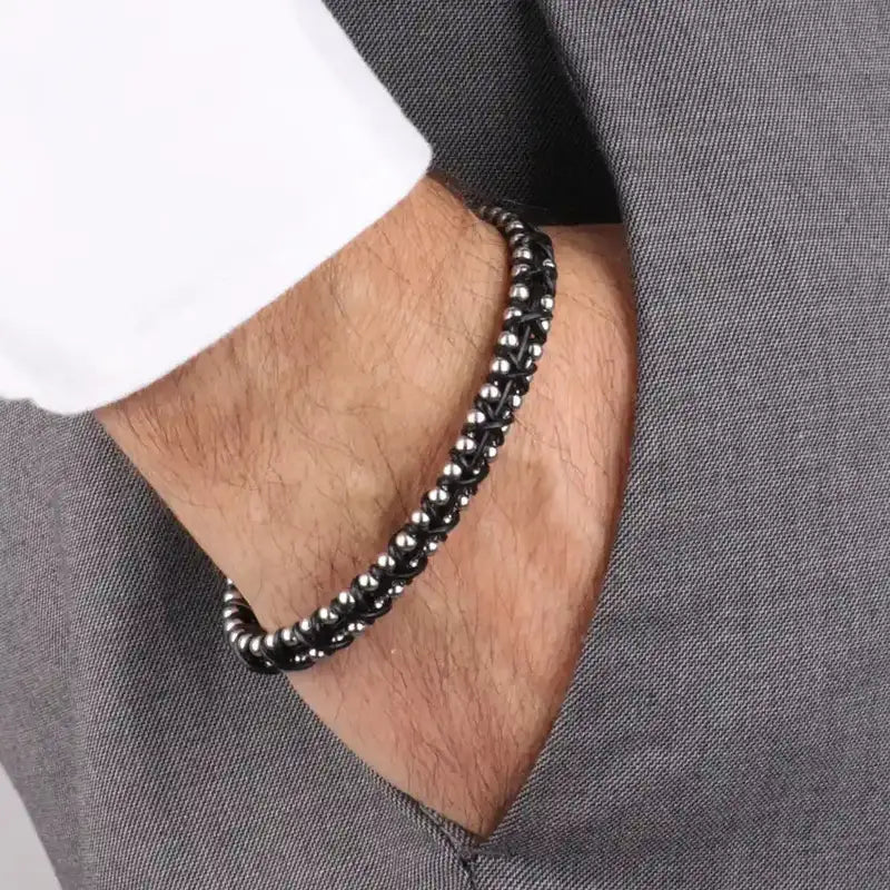 Bracciale in Acciaio rigido in corda nera intrecciata insieme a sferette in metallo lucido. Chiusura a scomparsa