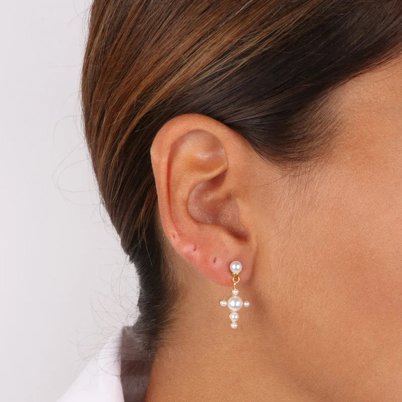 Metal pendant earrings in the shape of a cross embellished with white pearls