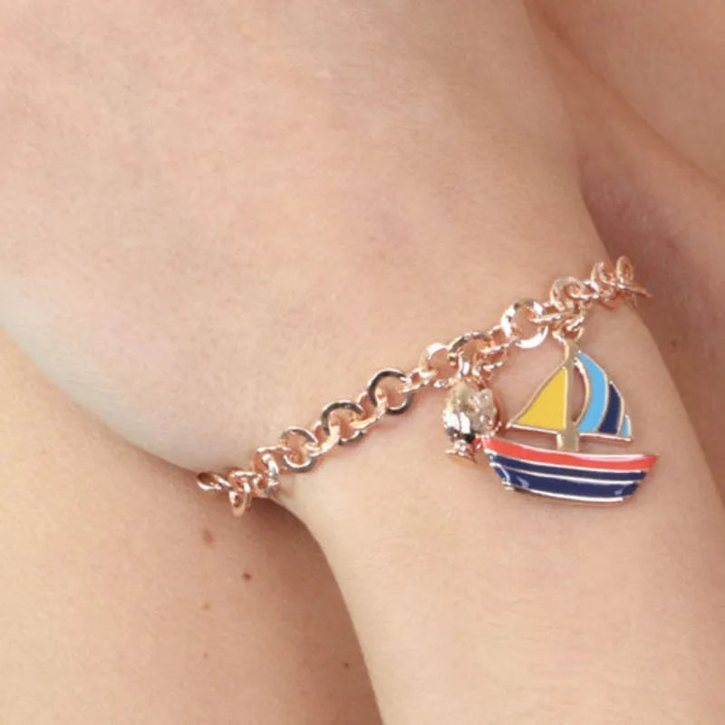 Metal bracelet with a dangling boat, embellished with colorful enamel and a mini pumo charm on the side