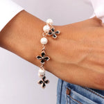 Bracciale in Metallo con perle bianche impreziosite da pendenti a forma di croce con smalto nero e cristalli bianchi