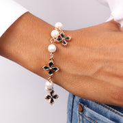 Bracciale in Metallo con perle bianche impreziosite da pendenti a forma di croce con smalto nero e cristalli bianchi